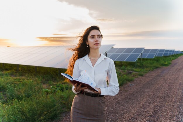 Girl reading près des rangées de panneaux solaires sur le terrain