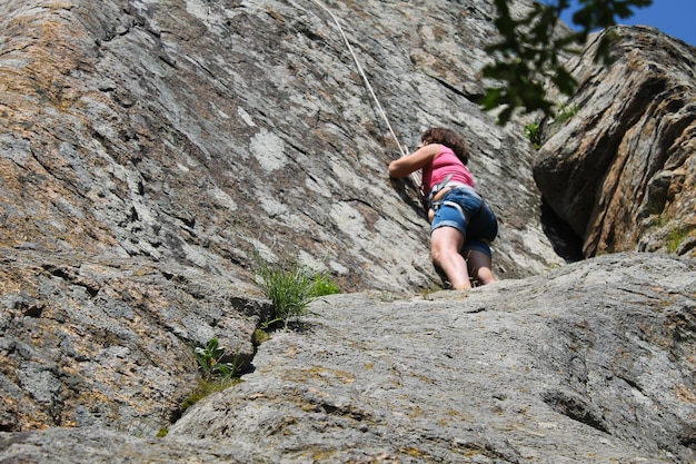 Girl rock climber grimpe sur un rocher