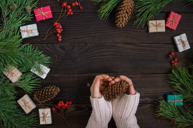 Girl's hands holding Christmas gift sur fond de branches de pin planches sombres