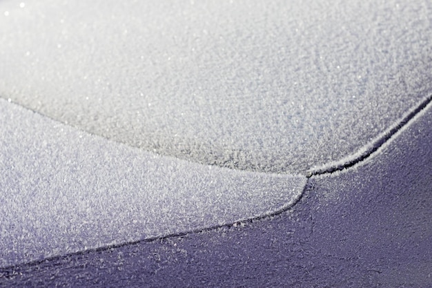 givre texturé sur la voiture sombre en journée d'hiver ensoleillée