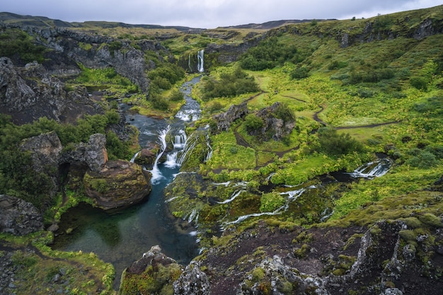 Gjain watrfall cascade roches de lave colorées vallée luxuriante mousse verte et végétation et eau bleue