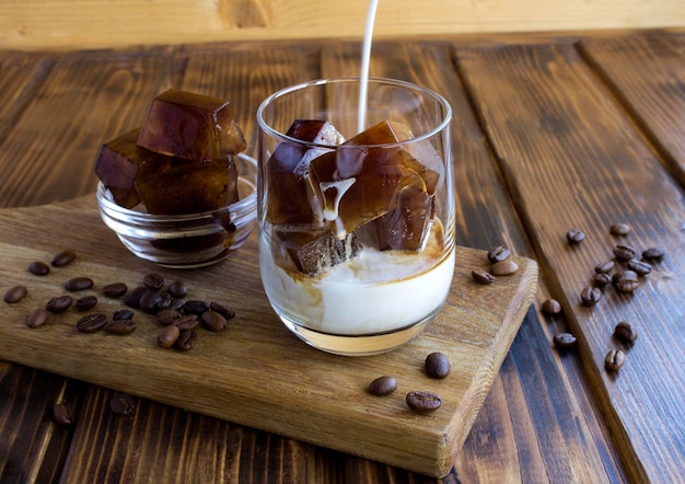 Glace au café congelé avec du lait dans le verre à boire sur le fond en bois Gros plan