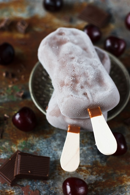 Glace au chocolat sur un bâton, avec fond cerise et rouillé