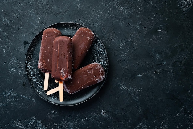 Glace au chocolat sur un bâton Sur fond noir Vue de dessus Espace de copie gratuit