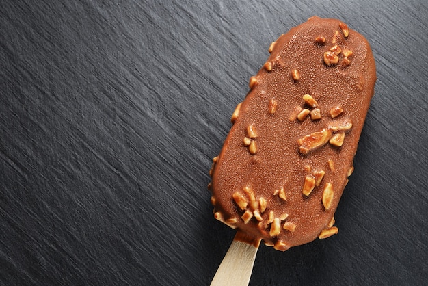 Glace au chocolat brun avec des arachides sur fond d'ardoise noire