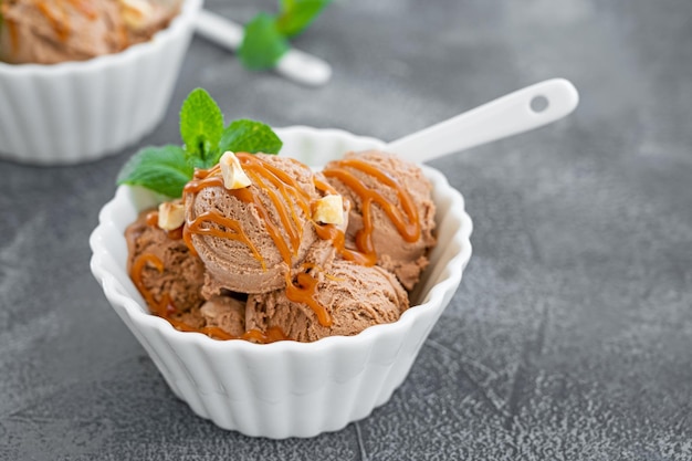 Glace au chocolat dans un bol avec sauce au caramel et noix sur fond sombre