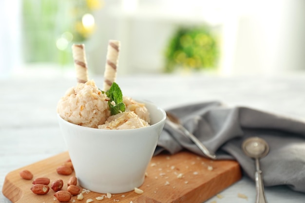 Glace au yaourt savoureuse dans un bol et noix sur planche de bois