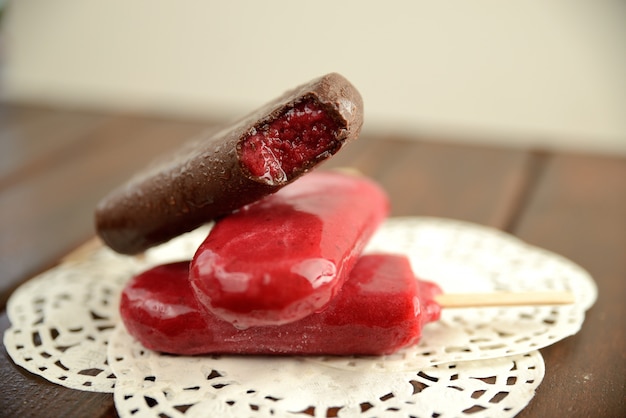 Glace aux fruits sur un bâton, sur fond de feuilles vertes