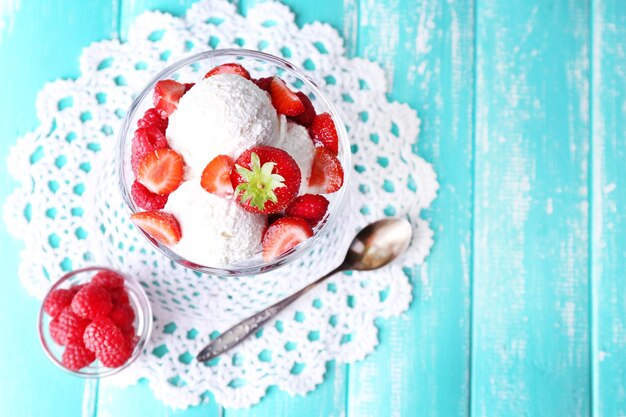 Photo glace crémeuse aux framboises sur plaque dans un bol en verre sur fond de bois de couleur