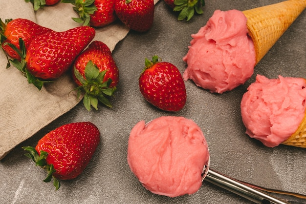 Glace à la fraise en cornet à biscuits, cuillère à glace, fraises et baies