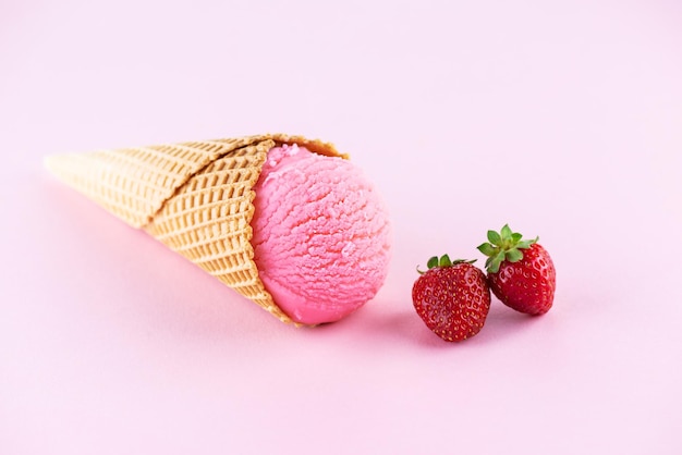 Glace à la fraise dans un cône sur fond rose