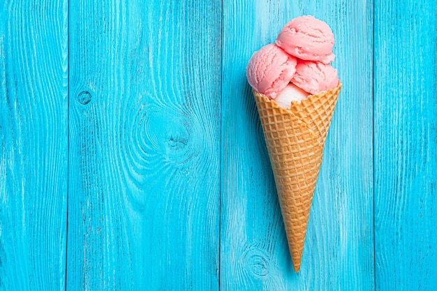 Glace à la fraise dans un cornet gaufré sur fond bleu