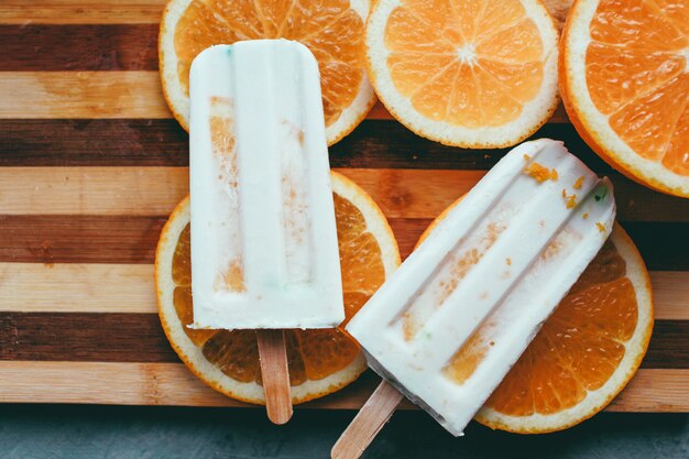 Une glace orange se trouve à côté du fruit sur un fond clair