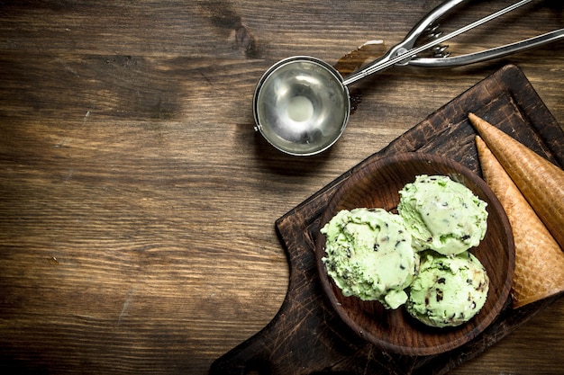 Glace à la pistache fraîche dans un bol avec des tasses à gaufres sur une table en bois