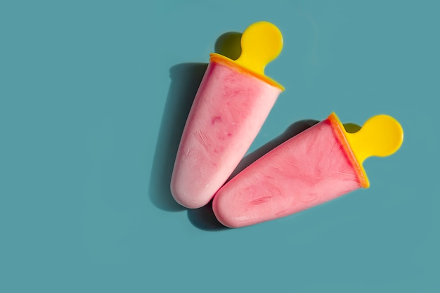 Glace rose faite maison. Popsicle naturel de fruits et de baies sans sucre par une chaude journée d'été. Mise à plat, vue de dessus, espace copie