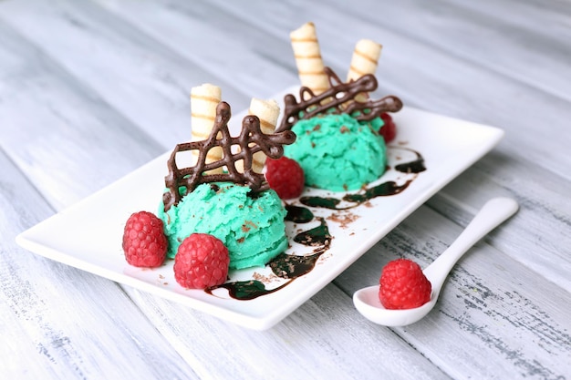 Glace savoureuse avec décorations au chocolat et assiette de sauce sur fond de bois de couleur