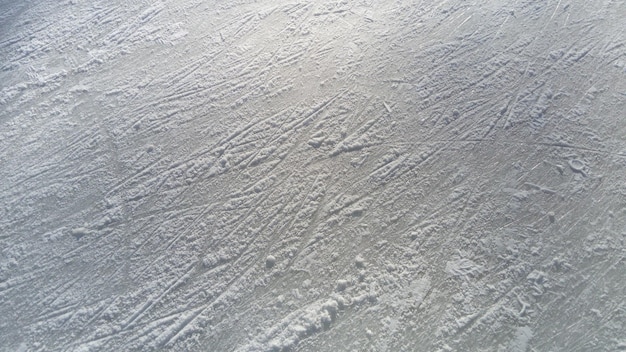 Glace striée avec la pointe des patins artistiques Patinage artistique sur glace La surface de la patinoire après l'exercice des patineurs Rayon de soleil sur la glace de printemps mouillée Neige et eau gelée