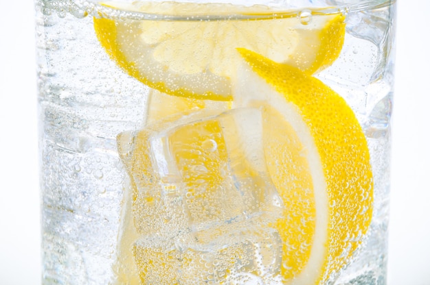 Glace, tranches de citron et eau cristalline dans un verre.