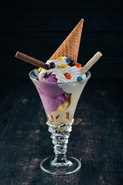 Glace à la vanille avec des bonbons colorés Sur un fond en bois noir Copiez l'espace