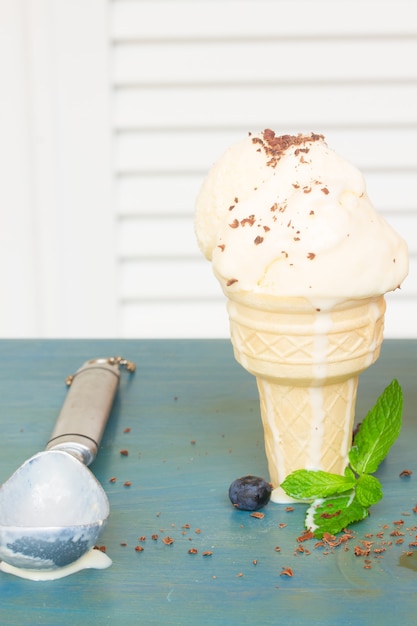 Glace à la vanille en cône avec cuillère vide sur table