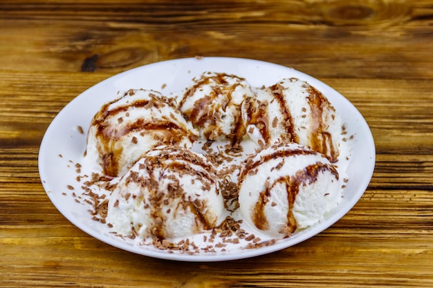 Glace à la vanille avec garniture au chocolat en plaque blanche sur une table en bois