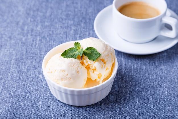 Glace vanille à la menthe dans une assiette blanche et une tasse d'espresso sur fond bleu. Glace maison. Fermer.