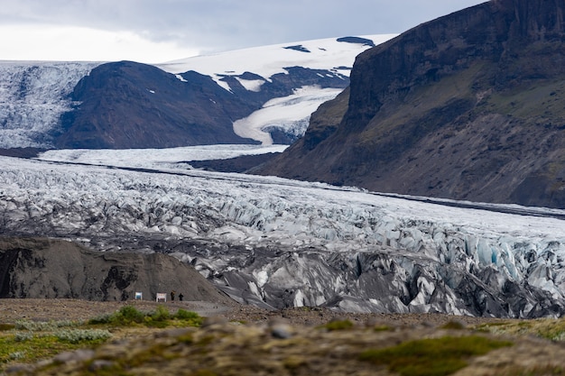 Glacier avec des cendres dans la glace avec de l'eau fondue et paysage islandais