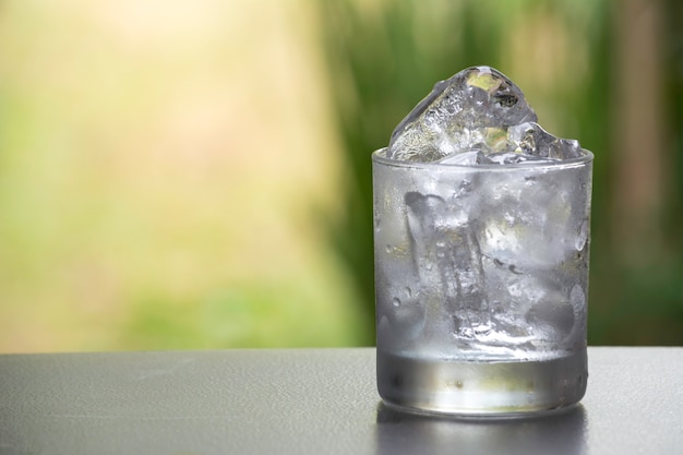 Glaçon dans le verre sur la table avec fond de nature