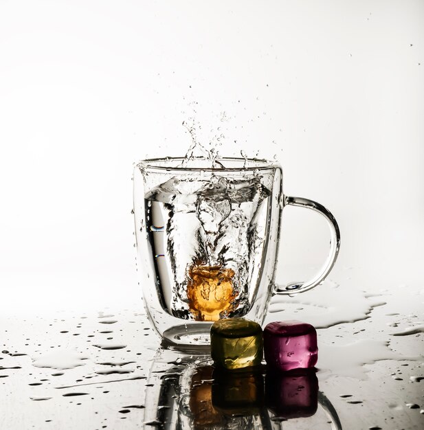 Glaçons éclaboussant dans un verre à boisson isolé sur blanc