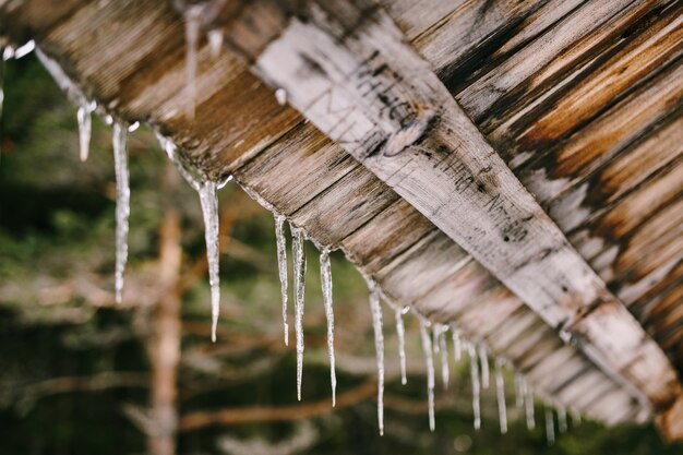 Les glaçons pendent d'un toit en bois au printemps