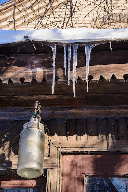 Des glaçons de printemps accrochés au toit de la vieille maison