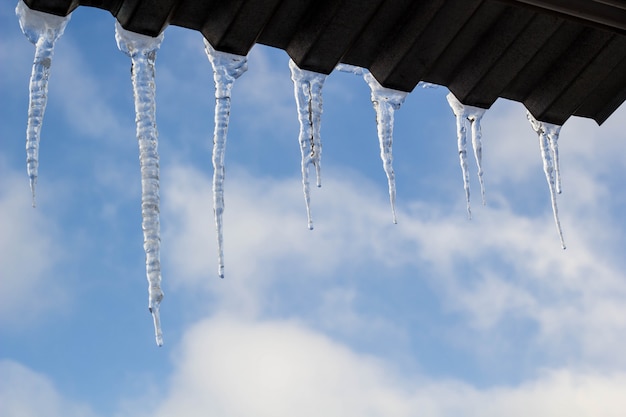 Glaçons Suspendus Sur Le Toit En Hiver. Formation De Glace Naturelle De Cristaux De Glace Suspendus Au Bord Du Toit En Hiver