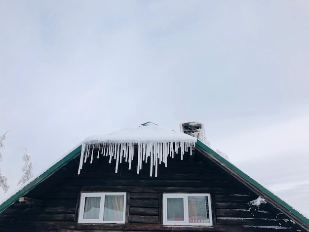 Des glaçons sur le toit d'une maison en bois