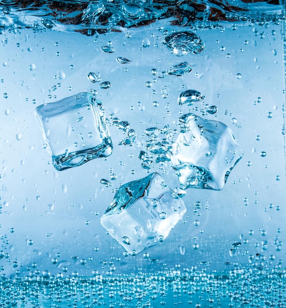 Des glaçons tombant dans l'eau coulant au fond. Contexte abstrait.