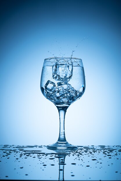 Des glaçons tombés dans un verre à cocktail faisant des éclaboussures.