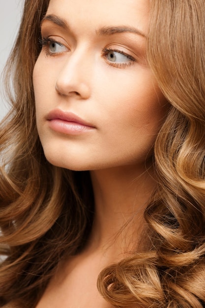 glamour, beauté et santé, concept - belle femme calme avec de longs cheveux bouclés regardant de côté