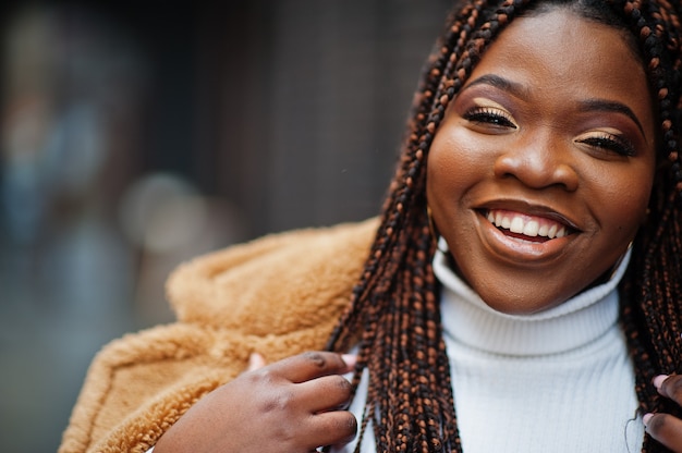 Glamour femme afro-américaine en manteau de fourrure chaud pose à la rue.