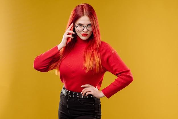 Glamour femme portant des lunettes à l'aide de smartphone sur fond jaune