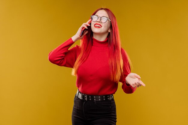 Glamour femme portant des lunettes à l'aide de smartphone sur fond jaune