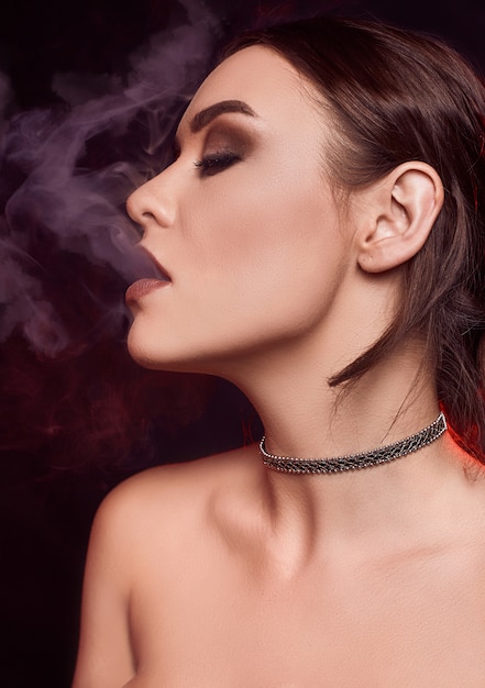 Glamour séduisante superbe femme brune fumer une cigarette électronique