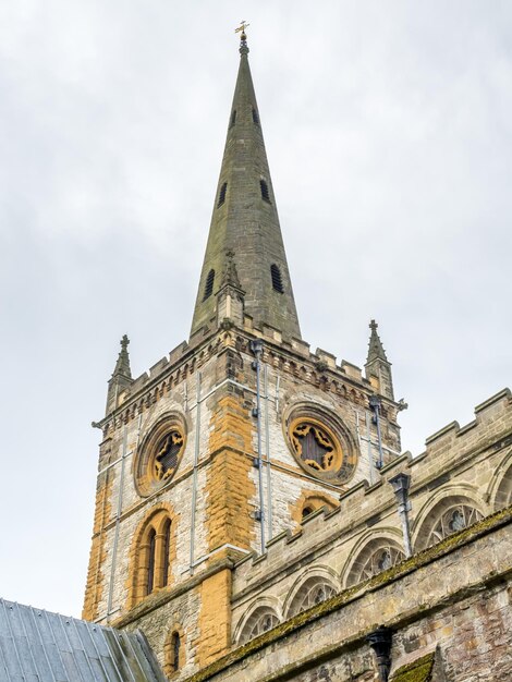 Église d'architecture gothique anglaise à Stratford avec parc environnant sous ciel nuageux