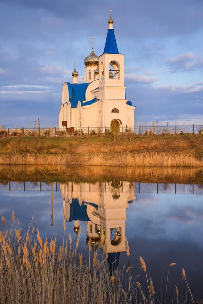 Église blanche au toit bleu sur le lac reflet de l'église dans le lac