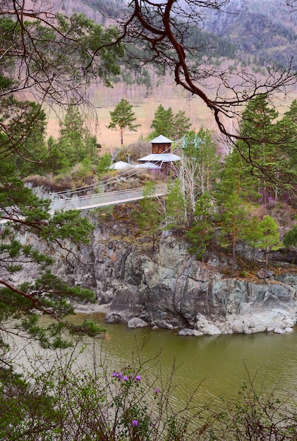 Église en bois sur la côte rocheuse escarpée du pont suspendu de Katun au-dessus de l'eau verte