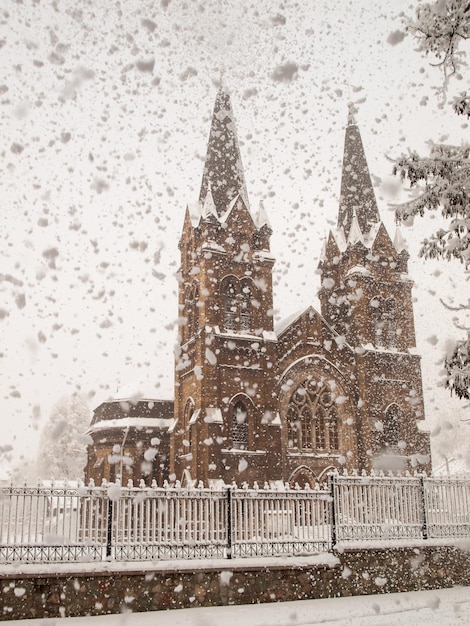 Église catholique romaine avec clôture en fer et arbres couverts de neige en hiver