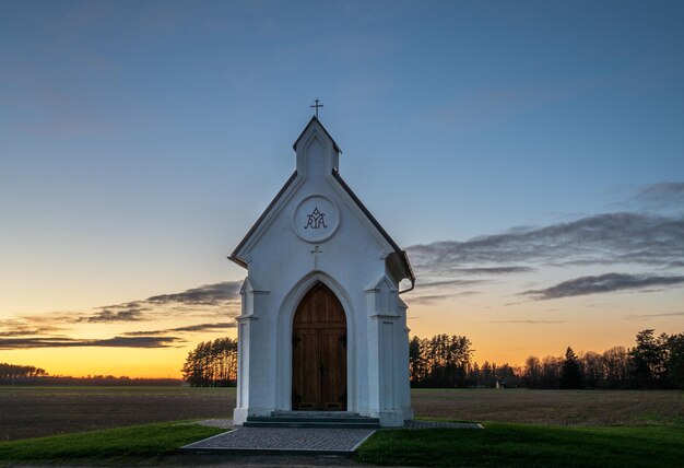 Église sur le champ contre le ciel au coucher du soleil