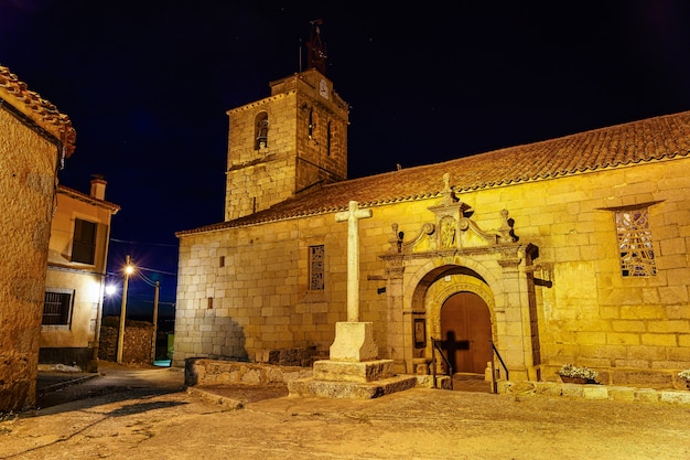 Église romane de nuit avec clocher et croix de pierre.