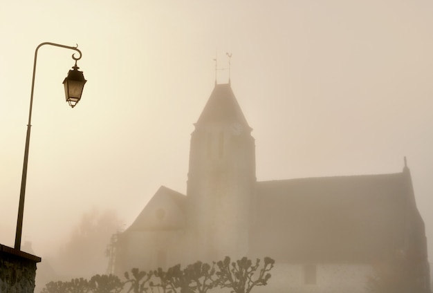 Église d'un village et d'un lampadaire dans le brouillard