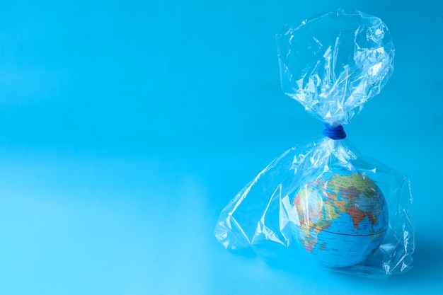 Globe enveloppé dans un sac en plastique avec espace de copie pour le texte sur fond bleu. Le concept de plastique p