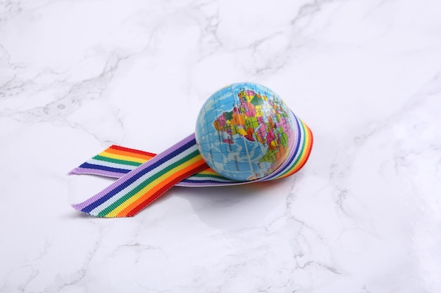 Globe avec symbole de bande de fierté de ruban arc-en-ciel LGBT sur fond de marbre Concept d'amour et de tolérance