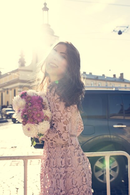 Glorieux modèle brune en robe tendance posant dans la rue avec une lumière parasite. Effet tonifiant vintage